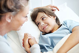 daughter in hospital bed holding mom's hand